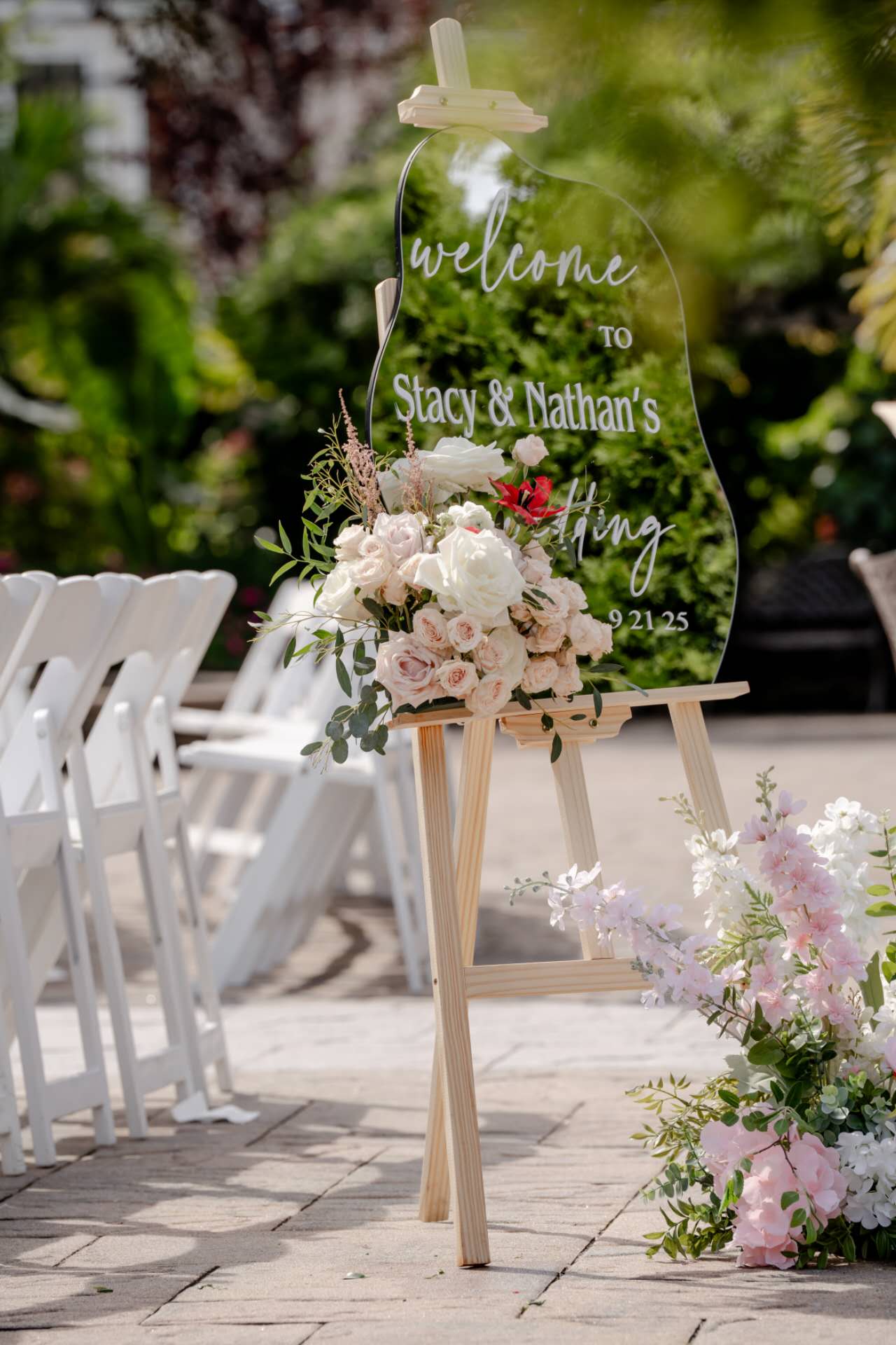 Decorative wedding sign with flowers on an easel outdoors