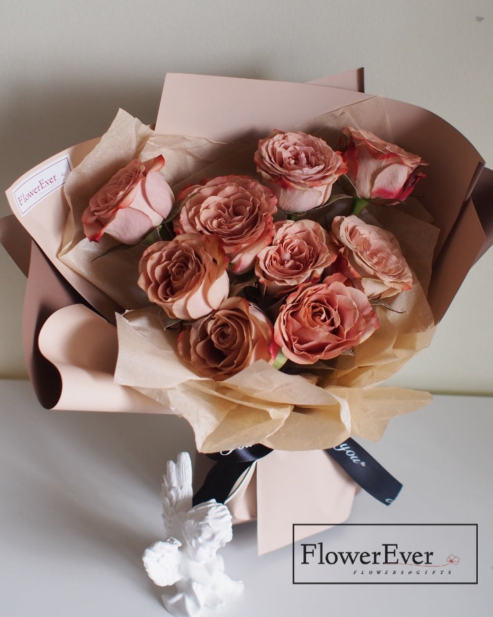 A floral arrangement composed of 12 stems featuring preserved white roses, caramel peach roses and mocha brown rose buds tied with a jute string.