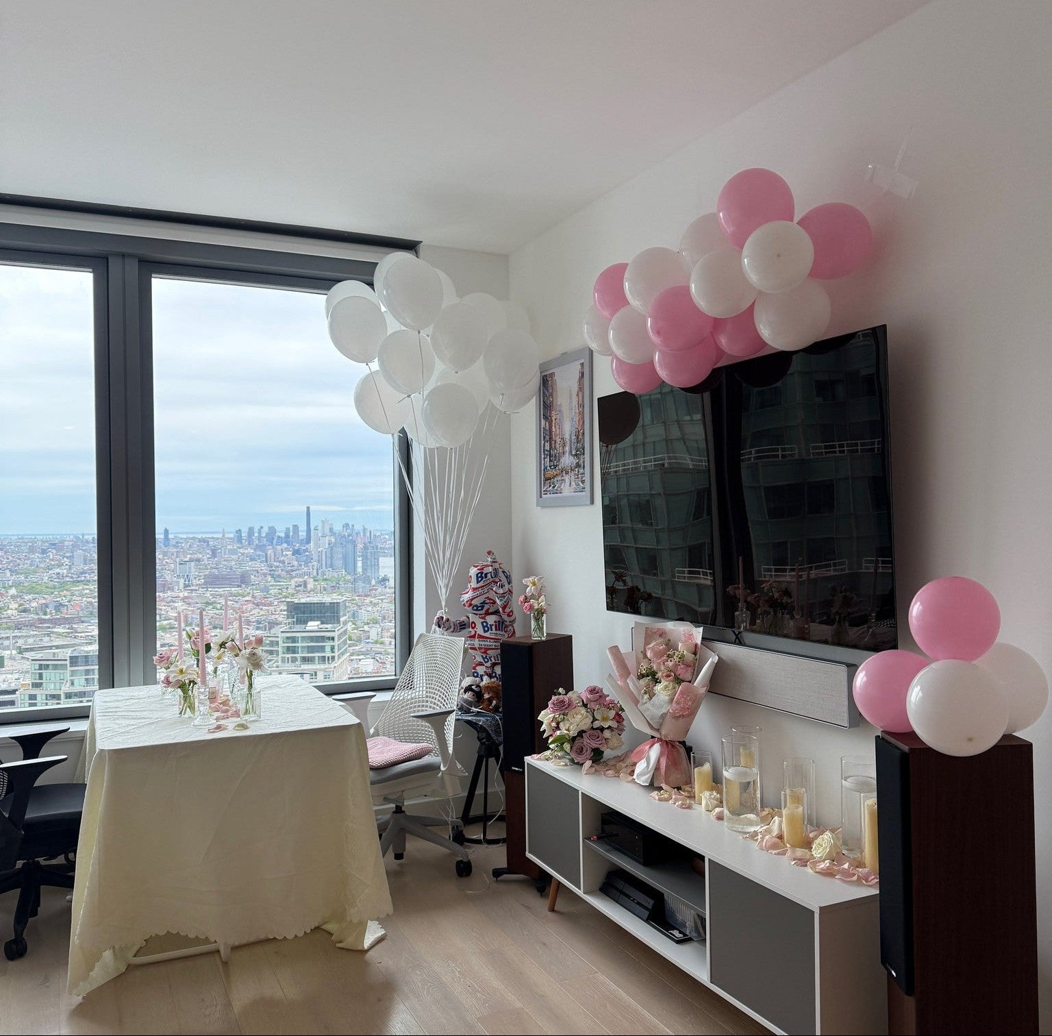 Living room with balloons, TV, and decor in a high-rise building.