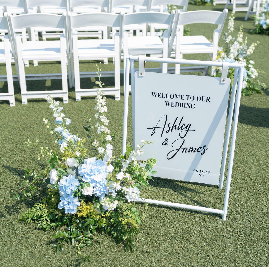 Wedding setup with white chairs, floral arrangements, and a welcome sign on a rooftop with cityscape in the background.