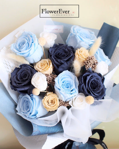 A floral arrangement containing 12 stems of vivid blue preserved roses complemented by cream and white blooms in neutral tones.