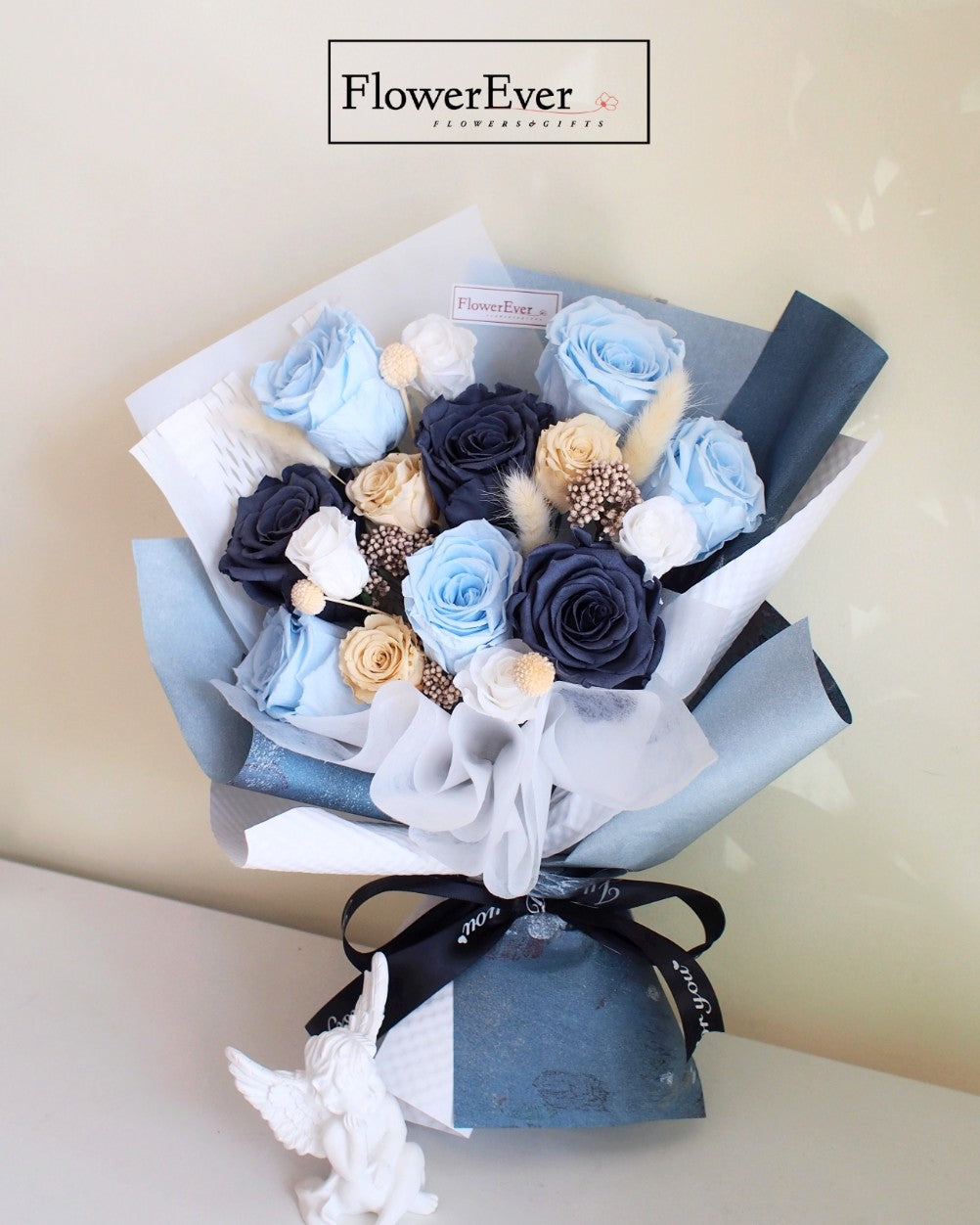 A mixed floral bouquet with 12 stems of blue preserved roses combined with nude and white blooms wrapped in craft paper.