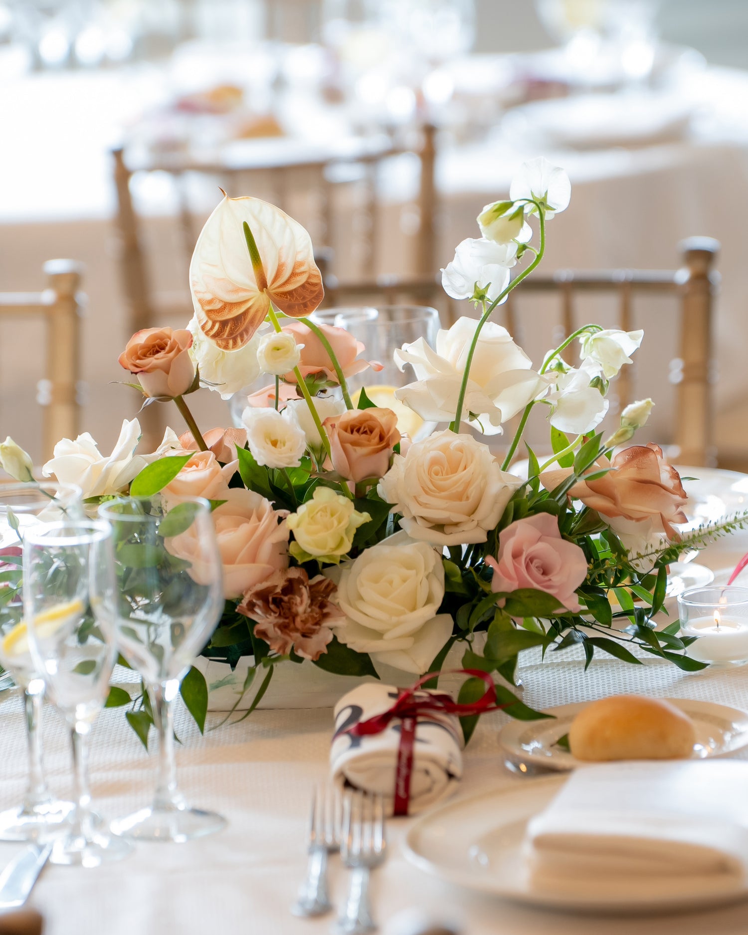 Floral centerpiece on a table with chairs and tableware in the background