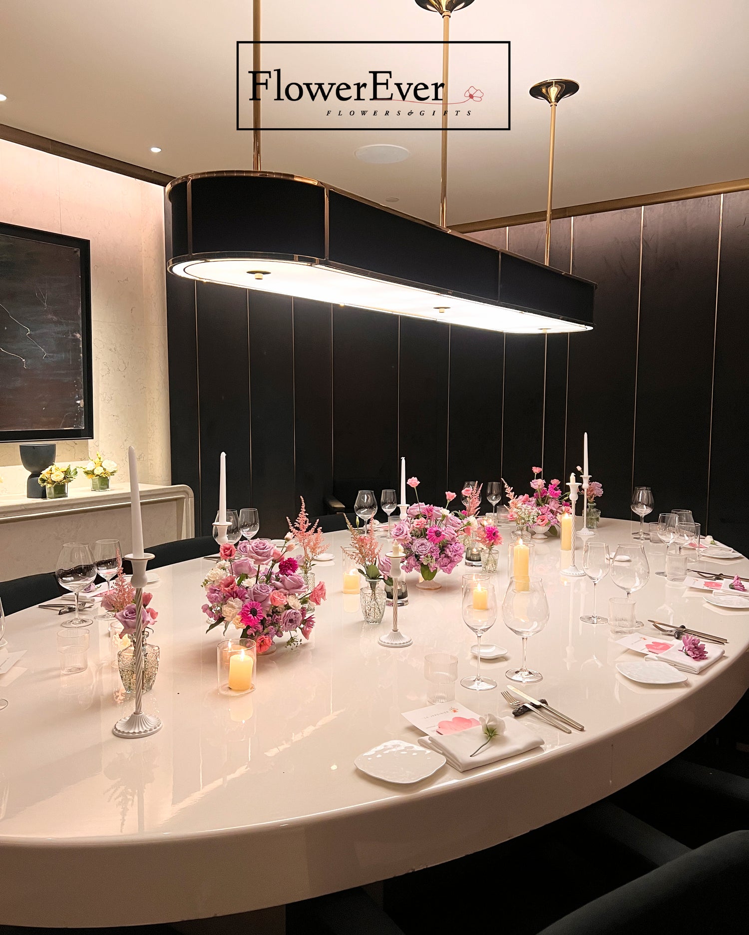 Elegant dining table setup with floral arrangements and candles in a modern interior setting, featuring the brand &