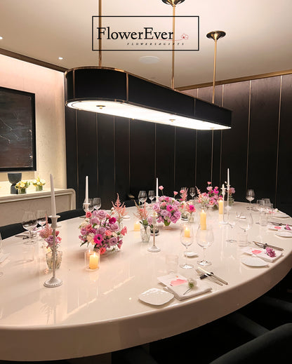 Elegant dining table setup with floral arrangements and candles in a modern interior setting, featuring the brand &