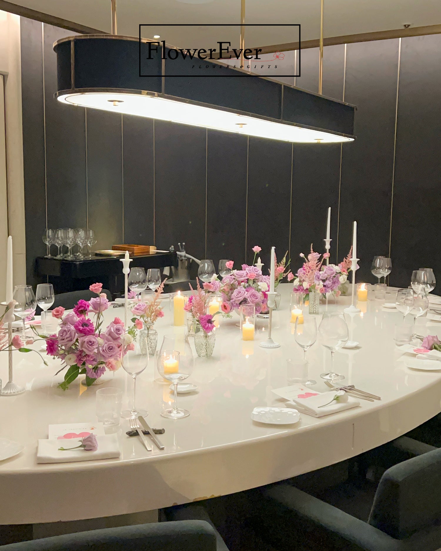 Elegant dining table setup with floral arrangements and candles in a modern restaurant setting.