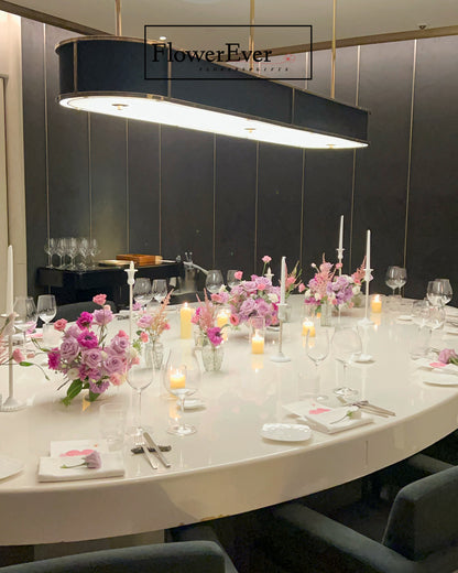 Elegant dining table setup with floral arrangements and candles in a modern restaurant setting.