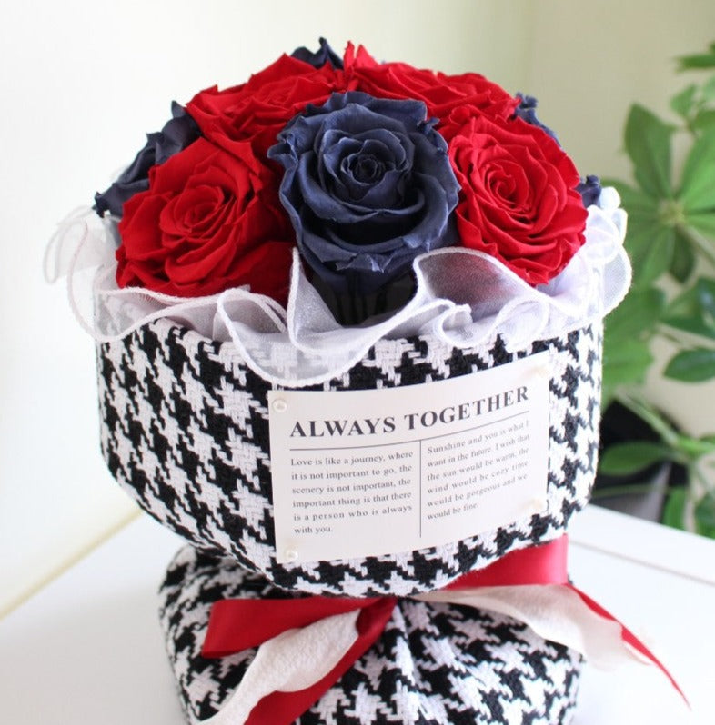 Twelve preserved rose stems in red and blue hues arranged in a Russian inspired bouquet with a Chanel houndstooth patterned paper.