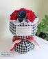 A Russian style floral bouquet with 12 stems of red and blue preserved roses arranged in a Chanel houndstooth paper wrap.