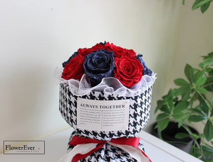 Twelve stems of preserved red and blue roses in a Russian style bouquet encased in a Chanel black and white houndstooth patterned paper.