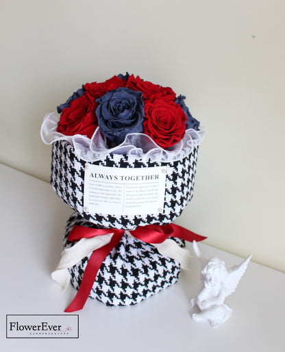 A floral arrangement of 12 preserved red and blue roses in Russian style presented in a Chanel-branded black and white houndstooth gift wrap.