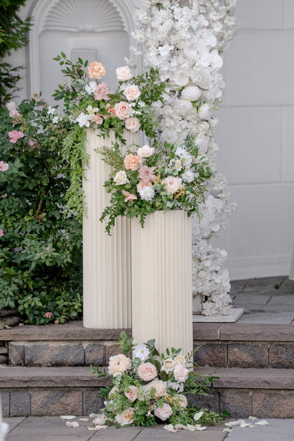 Floral archway with white and pink flowers on a stone staircase.