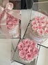 Three decorative boxes filled with pink roses on a white surface.