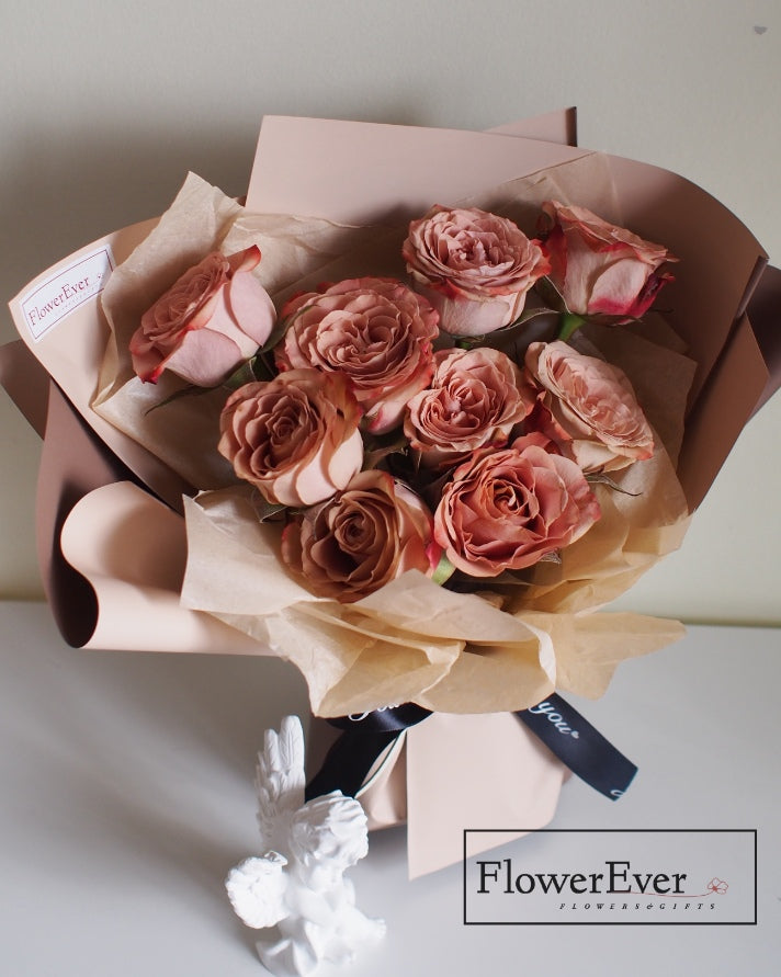 A floral arrangement composed of 12 stems featuring preserved white roses, caramel peach roses and mocha brown rose buds tied with a jute string.