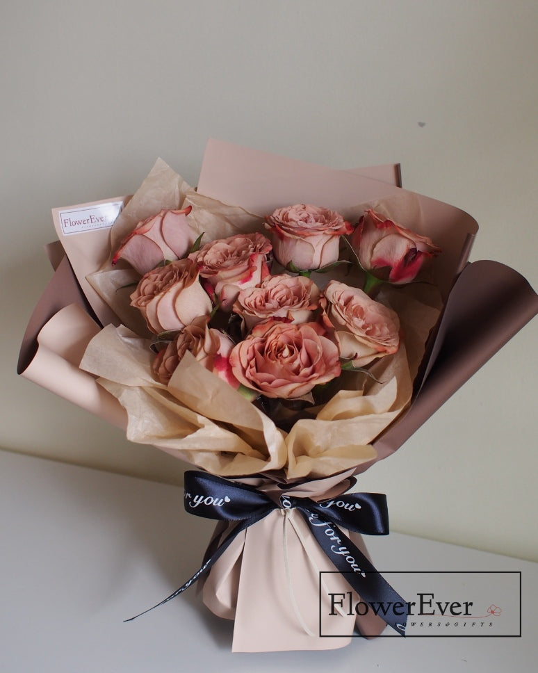 Twelve stems of preserved white, tan and brown roses at different blooming stages creating a vintage cappuccino-toned round floral bouquet arrangement with burlap bow.