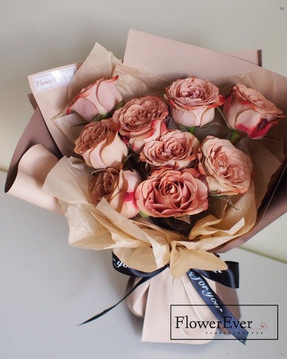 Twelve stems of preserved roses in creamy white, light brown and darker tan shades arranged in a vintage cappuccino-evocative round bouquet.