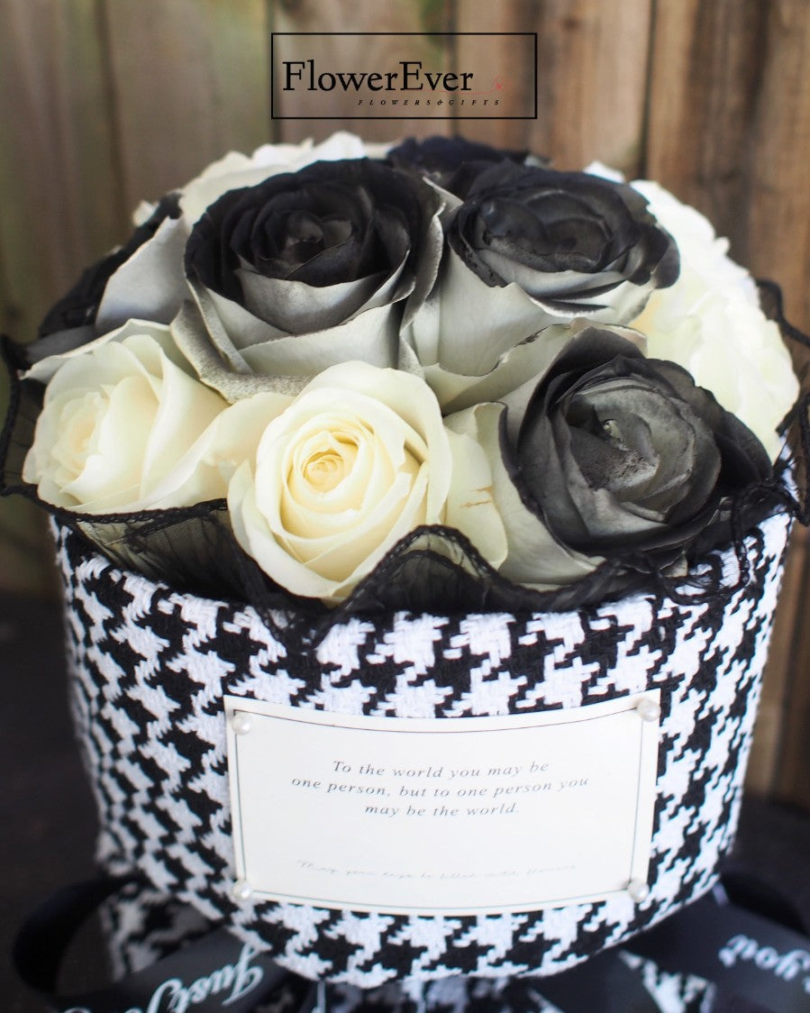 12 vivid preserved white and black roses arranged in a Russian-inspired floral bouquet wrapped in a black and white Chanel houndstooth paper sleeve