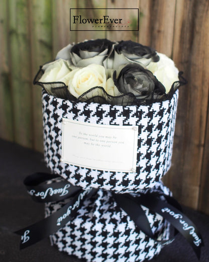 Luxury brand Chanel black and white houndstooth print paper wrapping a round classic Russian preserved rose bouquet with 12 black and white stems.