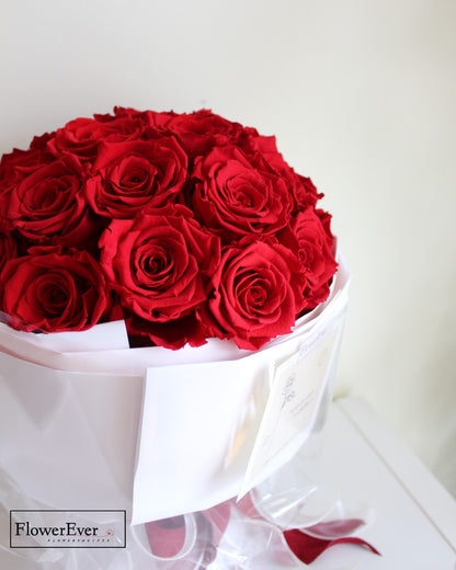 A round bouquet of 33 bright red preserved roses arranged in Russian inspired style in white gift wrapping.