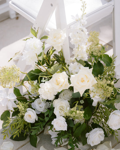 Bouquet of white flowers with greenery on a white wooden surface