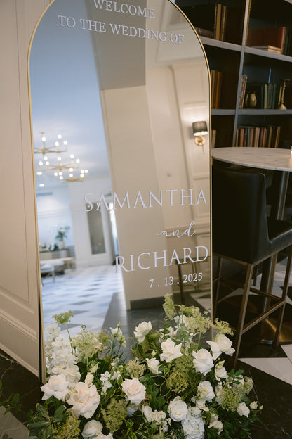 Decorative mirror with personalized text in a room with flowers and furniture.