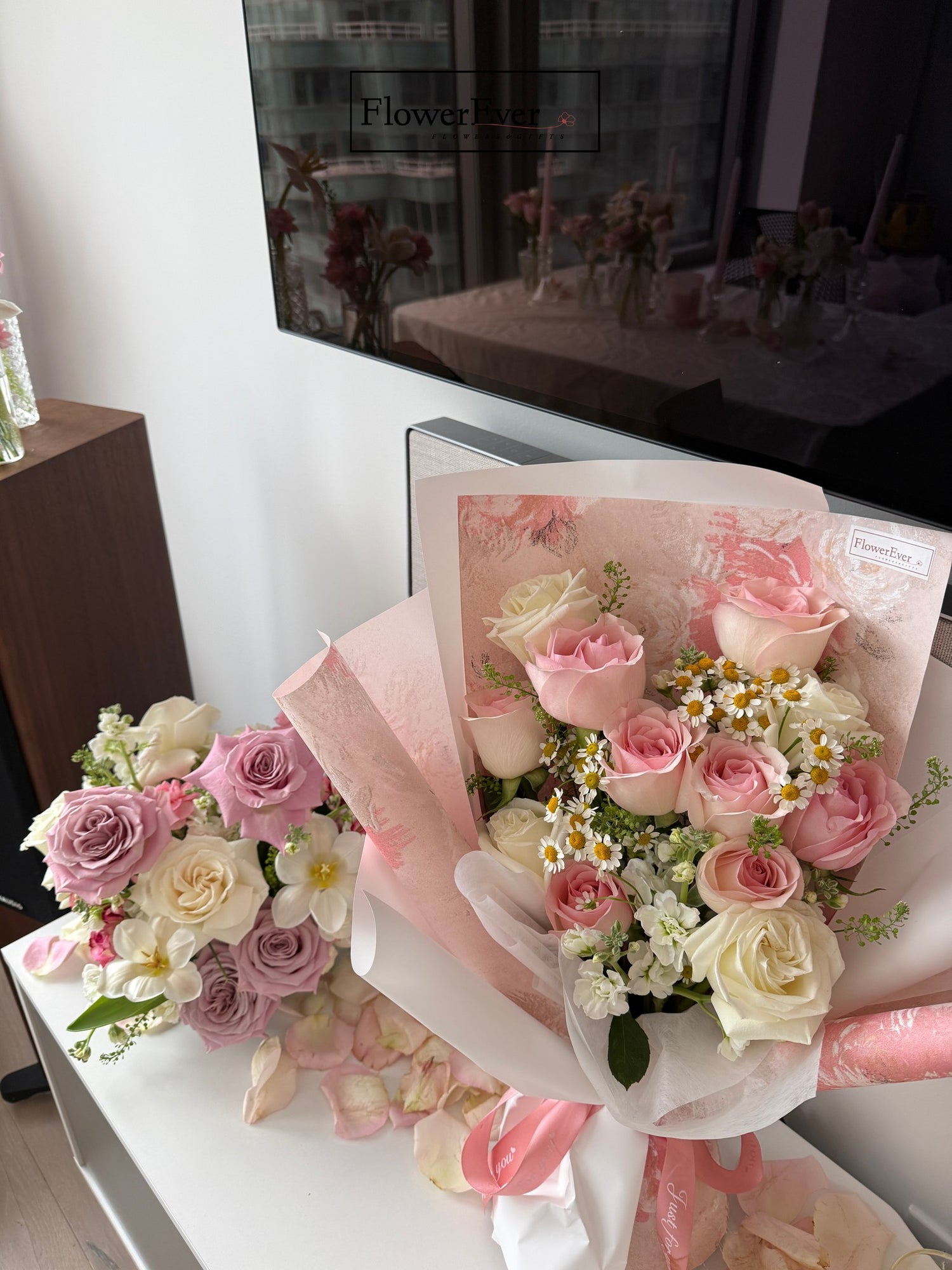 Bouquets of pink and white roses with decorative paper on a table.