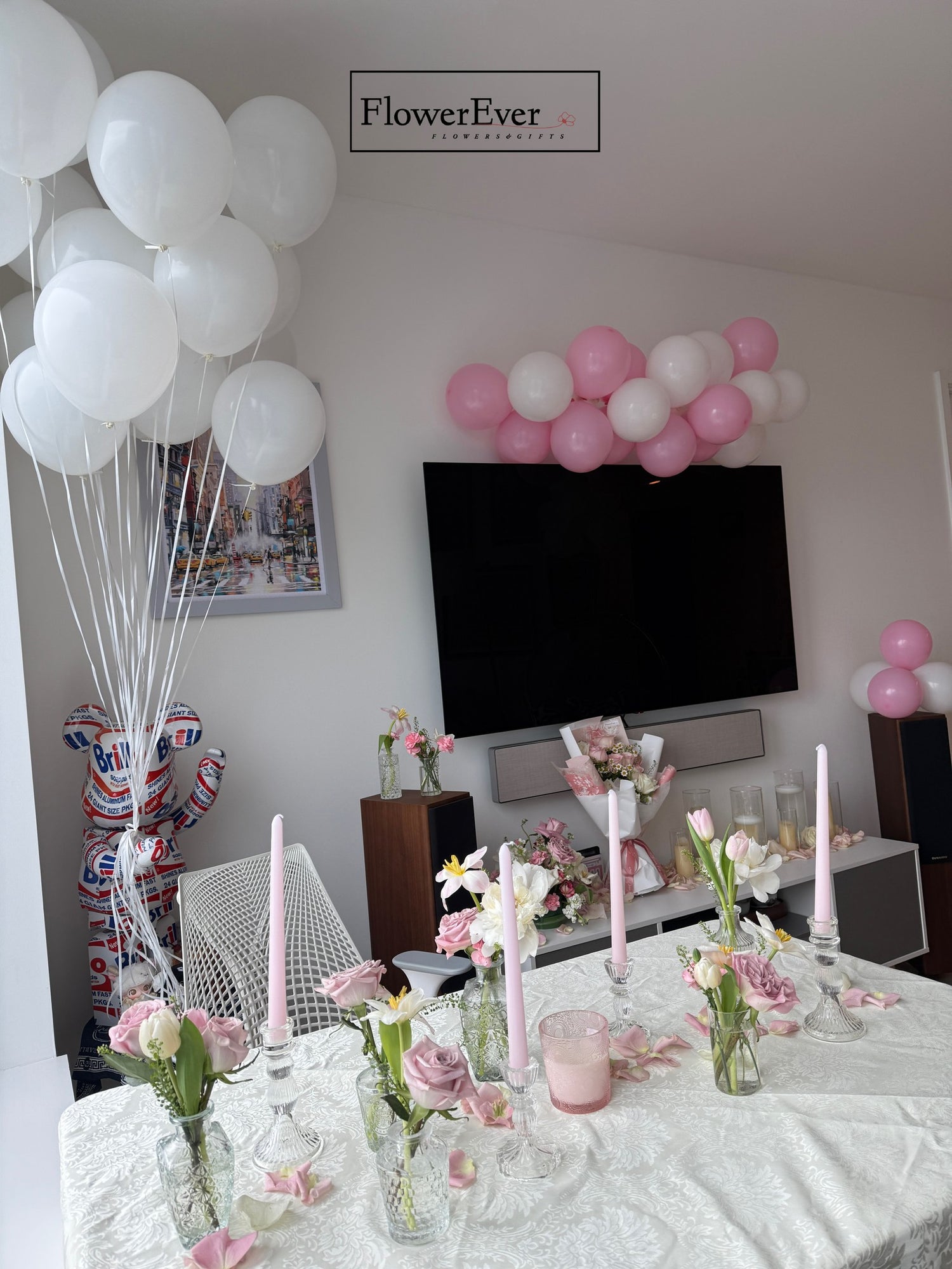 Decorated room with balloons, flowers, and a TV in the background.