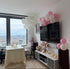 Living room with balloons, TV, and decor in a high-rise building.