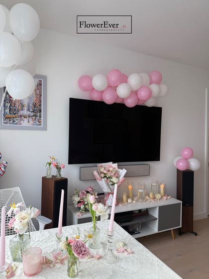 Decorated living room with balloons, flowers, and candles in a home setting.