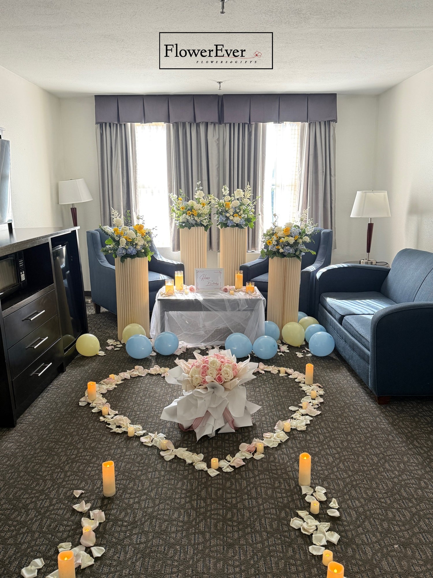 Decorative setup with flowers, candles, and balloons in a living room.