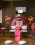Decorative setup with floral arrangements, red and white chairs, and a large circular sign in a room.