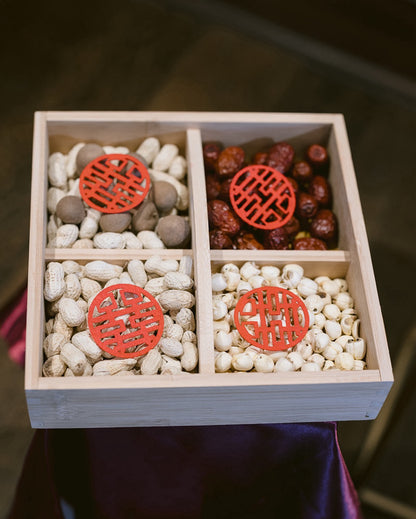 Wooden box with compartments filled with beans and red decorative elements on a dark background